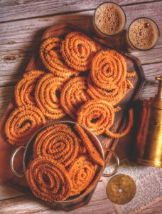 Enjoy traditional Indian chakli snacks served with tea, captured in a warm, rustic setting.