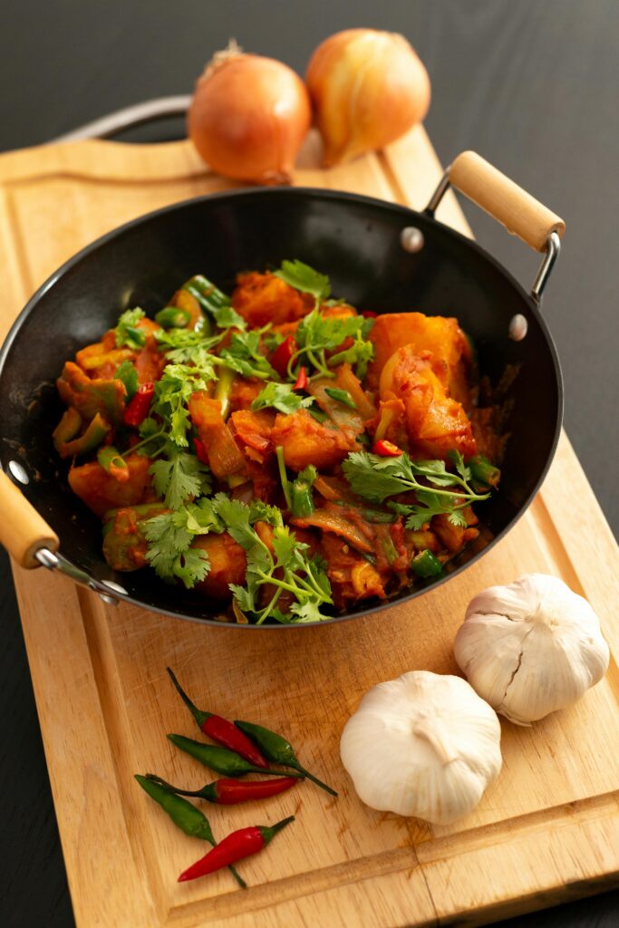 Colorful vegetable stir-fry in a wok with fresh ingredients on a wooden board.